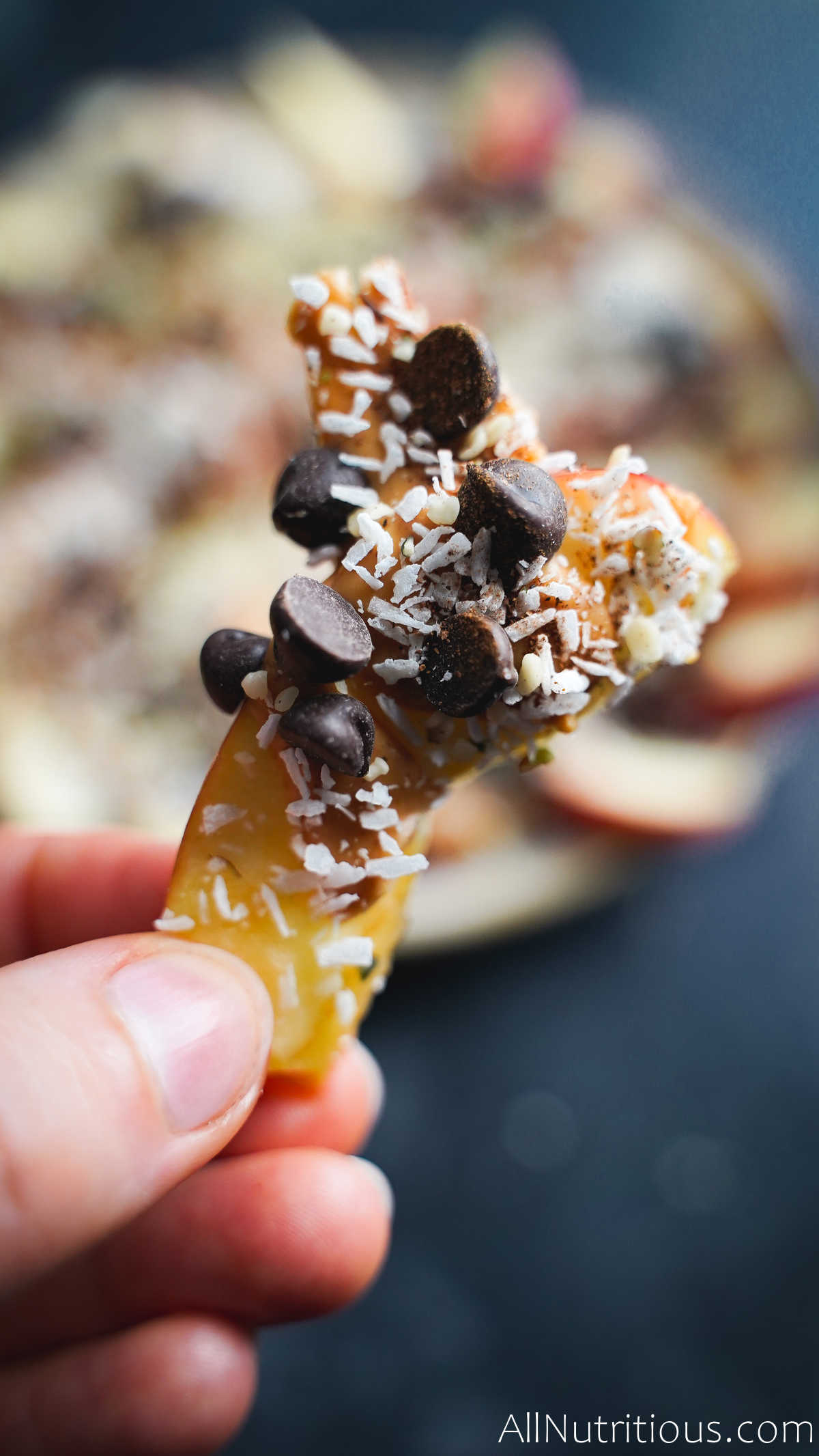 holding an apple slice with toppings