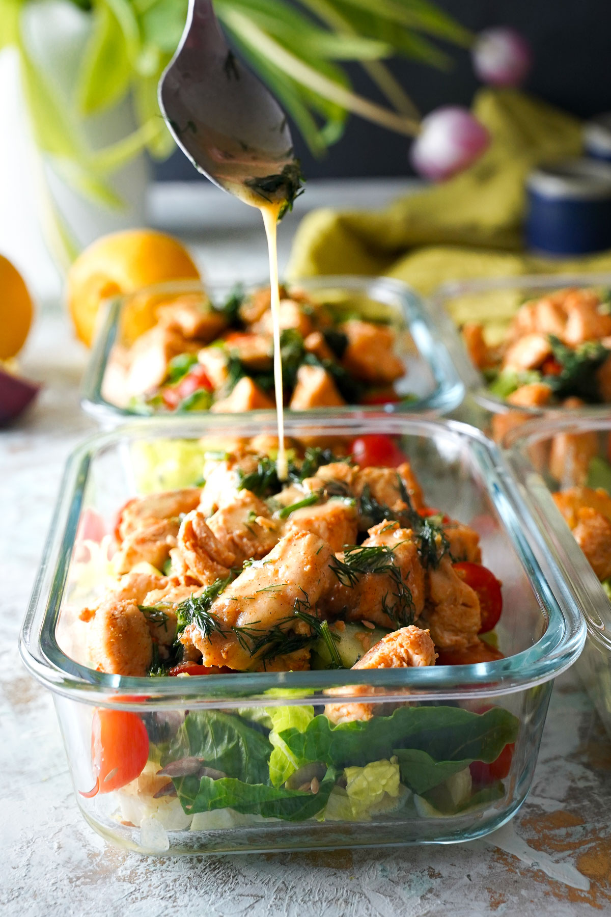 spoon drizzling dressing over chicken salad